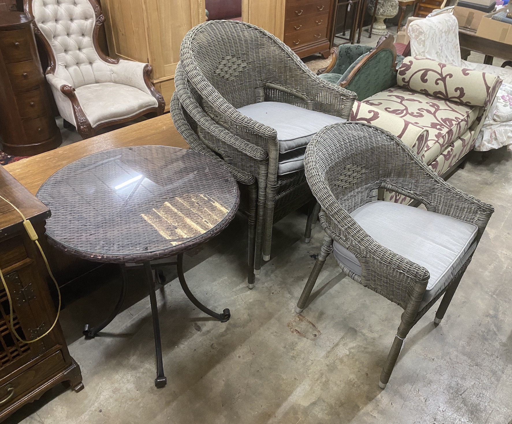 A set of four all weather faux rattan garden armchairs with seat cushions and a similar circular wrought iron and glass top garden table, diameter 68cm, height 72cm